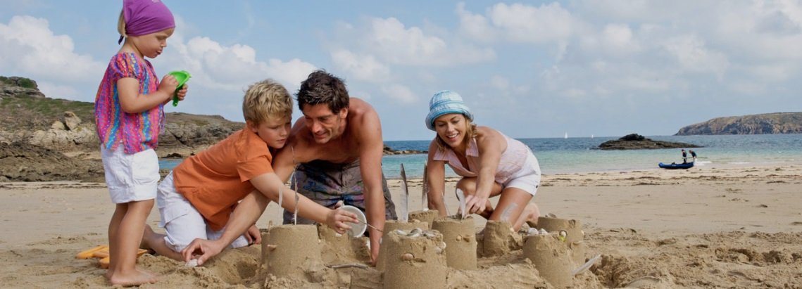Famille avec deux enfants jpouant dans le sables de nos plages bretonnes