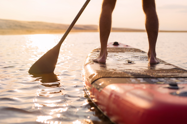 homme sur un paddle en fond de coucher de soleil